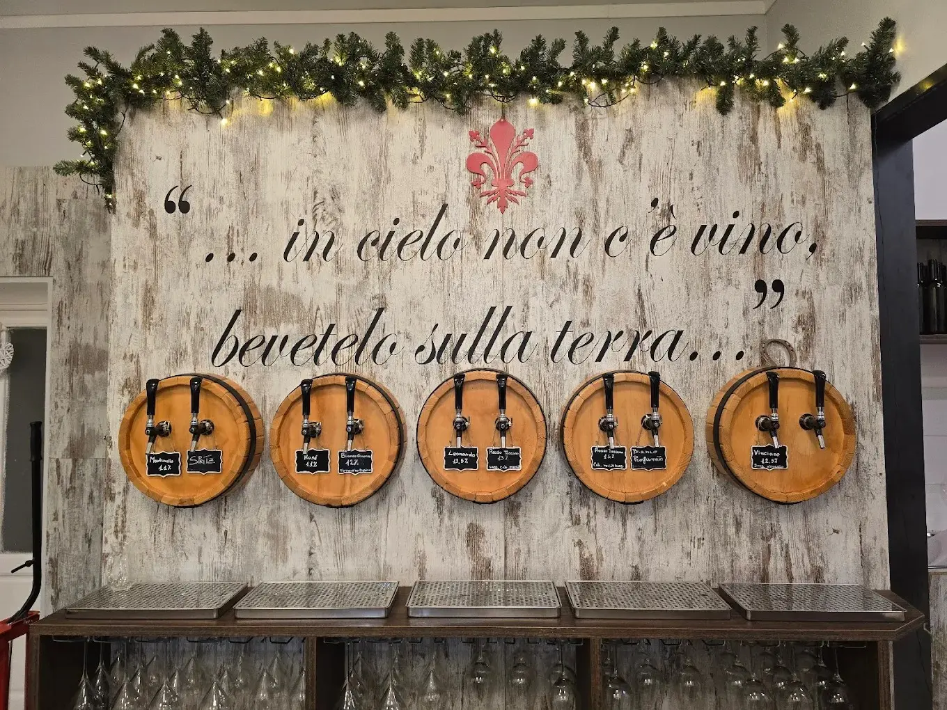 Interno dell'enoteca Dino Divino: tavoli in legno, bottiglie e luci calde